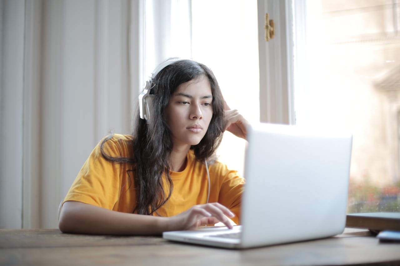 services-06 Young woman in headphones focused on laptop work, conveying a digital nomad lifestyle.